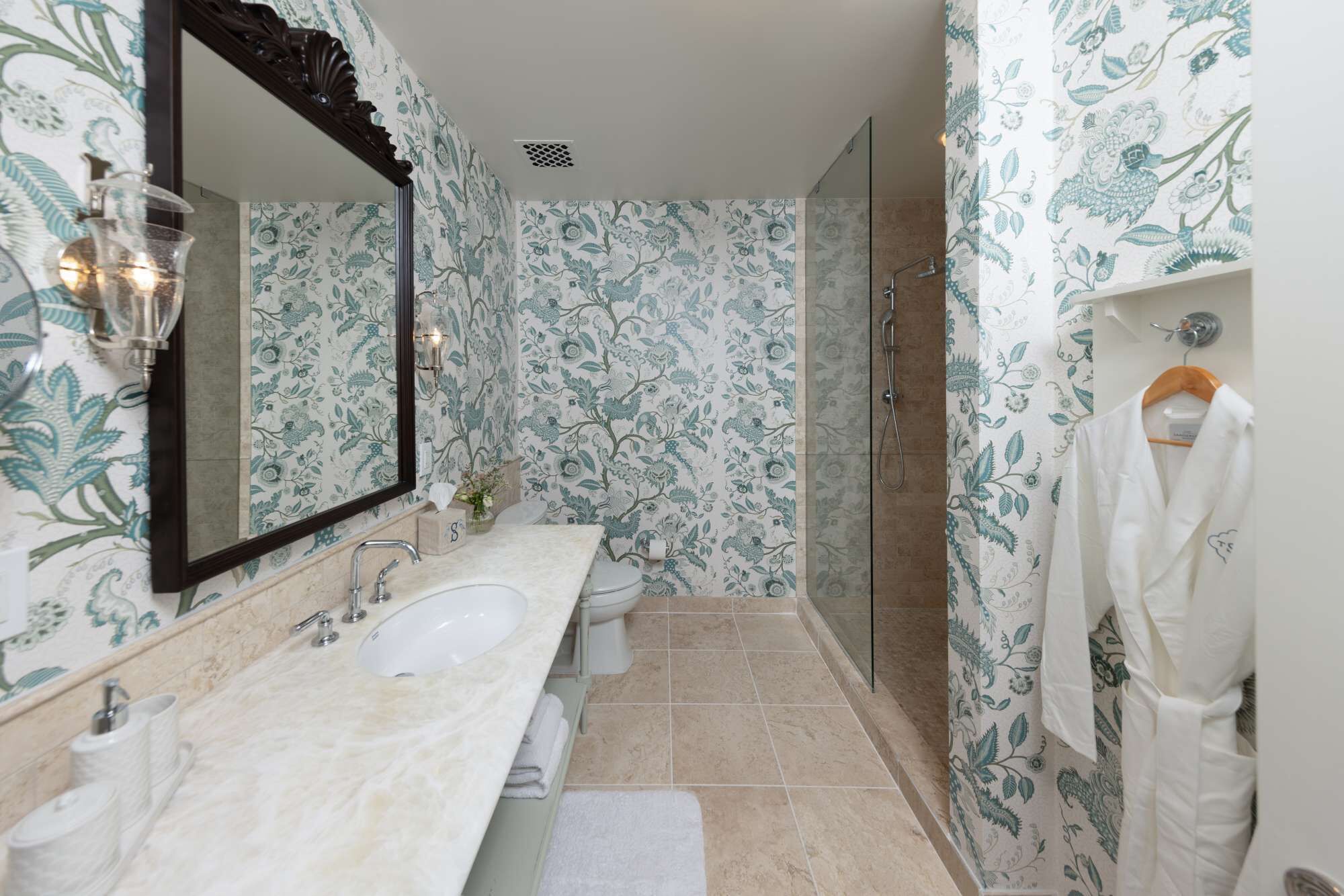 A bathroom with a double sink, a toilet, a shower, and a mirror.