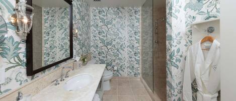 A bathroom with a double sink, a toilet, a shower, and a mirror.