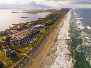 An aerial view of a coastal hotel with multiple buildings, a beach, and a marina. - King with Direct Pool Access + Restaurants & Spa (Duck)