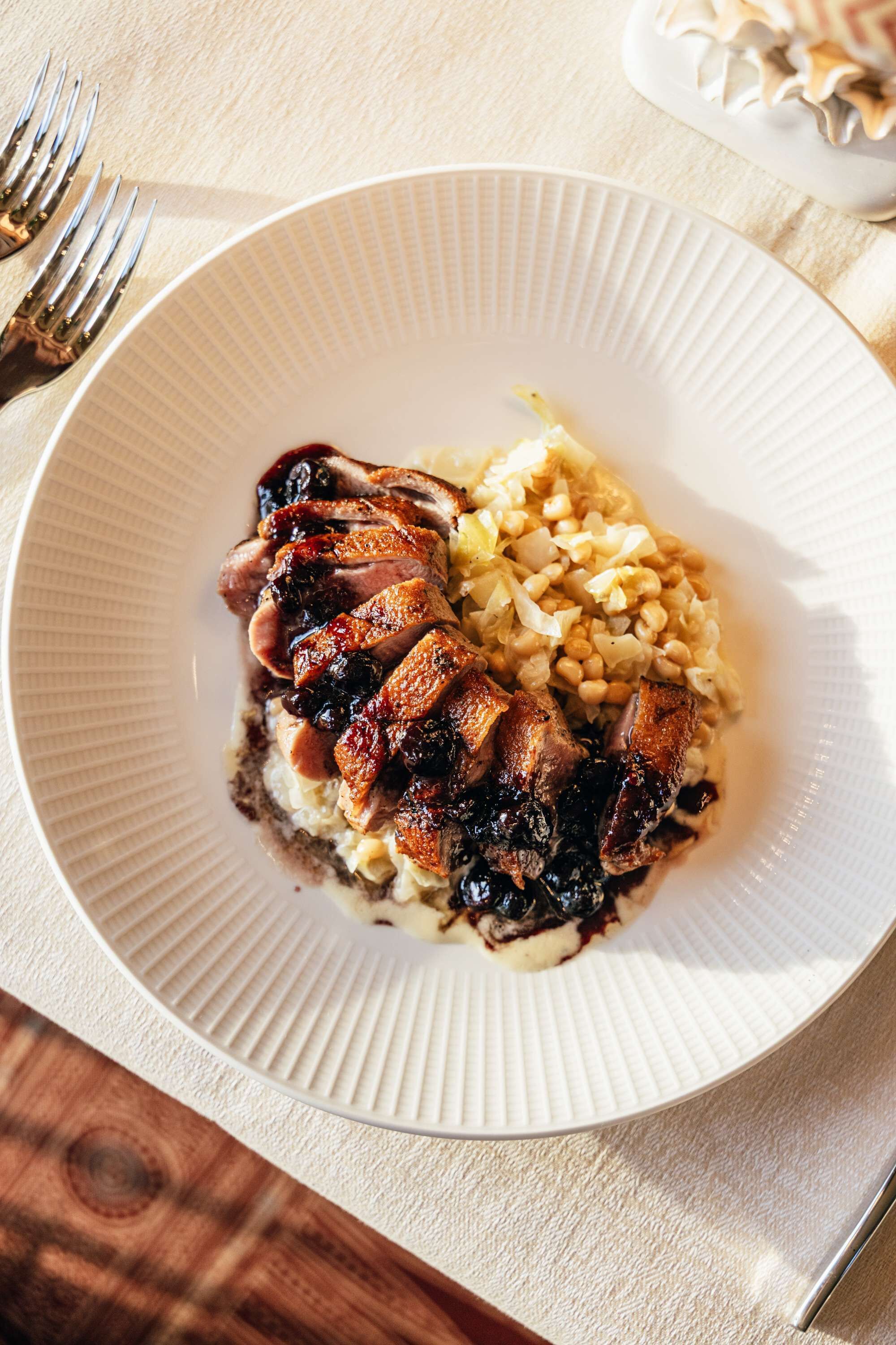 A plate with sliced meat and corn on a textured white plate.