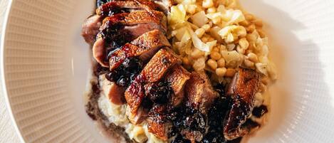A plate with sliced meat and corn on a textured white plate.