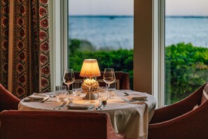 A dining table set for two with a view of the sea. - 2 Queens with Direct Pool Access + Restaurants & Spa (Duck)