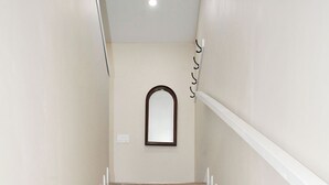 Uma escadaria com degraus de madeira e corrimãos brancos, que leva a um patamar com um espelho.