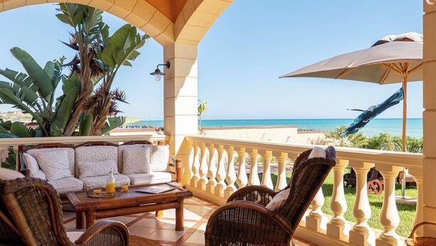 A balcony with wicker furniture, a table with a drink, and a view of the sea. - Seaside villa, suitable for families and friends, only 5 minutes from the Valley of the Temples. (San Leone)