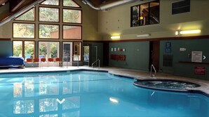 Ein Hallenbad mit Whirlpool, großen Fenstern und Blick auf Bäume.