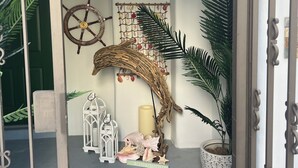 Un espace intérieur agrémenté d’un mur décoratif orné d’un gouvernail de navire, d’une structure tissée et d’une décoration murale composée de coquillages.
