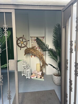 Ein Innenraum mit dekorativer Wand, die ein Schiffsschwengel, eine gewebte Struktur und ein Wandbehang mit Muscheln zeigt.