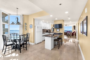 Una cocina moderna con una isla central, armarios blancos y vistas al exterior.