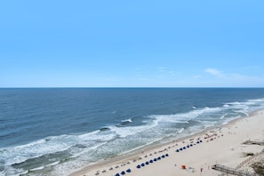 Ein Strand mit Reihen von Sonnenschirmen, sandigem Ufer und dem Ozean.