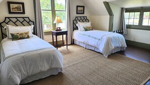Een slaapkamer met twee bedden, een nachtkastje, een lamp en een raam met gordijnen.