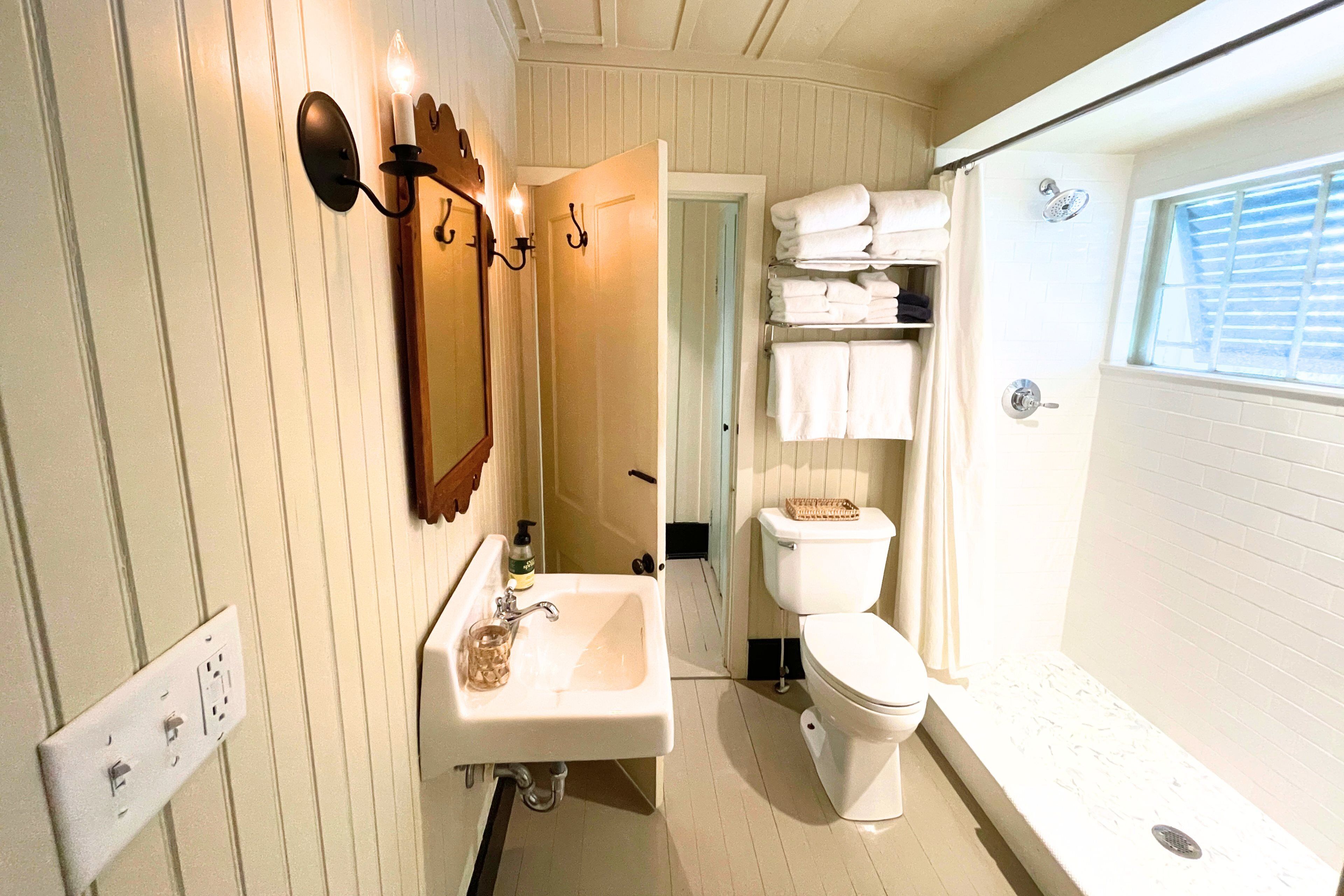 Ein Badezimmer mit Waschbecken, Spiegel, Toilette und Duschbereich.