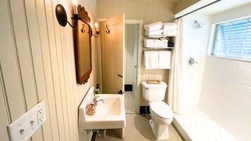 Ein Badezimmer mit Waschbecken, Spiegel, Toilette und Duschbereich.