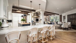 A spacious kitchen with a large island, bar stools, pendant lighting, and a view to the dining area. - Gated 7BR Rancho Santa Fe Estate Pool/Guest House (Rancho Santa Fe)