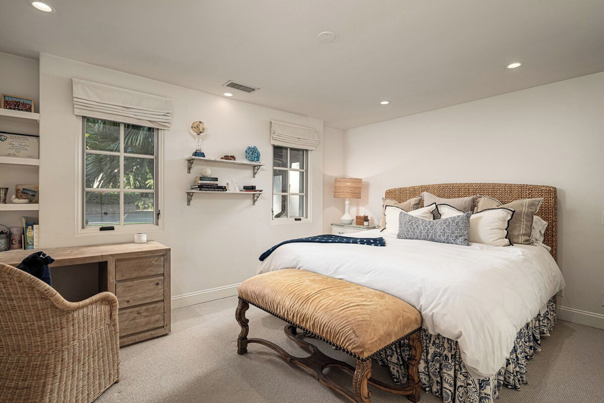 A bedroom with a bed, bedside table, lamp, and a desk with a chair.