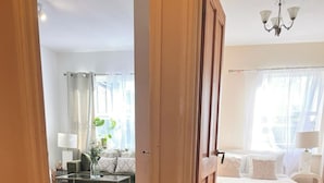 Ein Zimmer mit Holzboden, einem Bett mit weißer Bettwäsche, einer Couch und einer Lampe.
