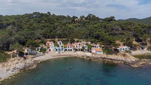 Un pueblo costero con edificios coloridos, aguas turquesas cristalinas y una ladera cubierta de bosque.