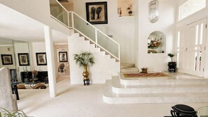 Un intérieur spacieux avec un escalier, un grand miroir et un coin repas.