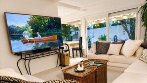 Un salon équipé d’un téléviseur, d’un canapé, d’une table basse et offrant une vue sur un jardin.