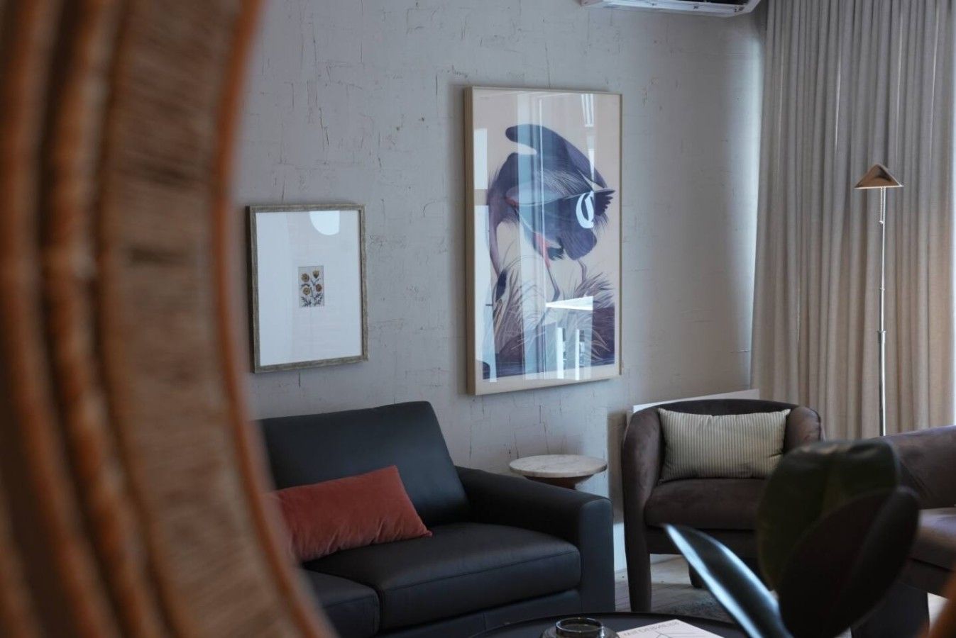 A living room with a black sofa, a round side table, and a framed picture on the wall.
