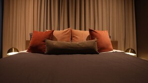 Un lit avec plusieurs oreillers, une tête de lit et deux lampes de chevet.