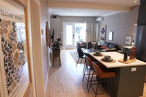 Une cuisine moderne dotée d’un îlot central, d’un coin repas avec des chaises et d’un salon avec un canapé et une table basse.