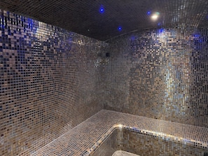 A room with a tiled wall and a curved bench.