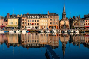 A harbor with boats docked, a church steeple, and buildings with shops.