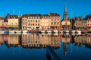A harbor with boats docked, a church steeple, and buildings with shops. - Charmant studio à deux pas de Honfleur | Piscine (Gonneville-sur-Honfleur)