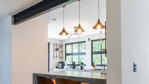 A modern kitchen with a bar area, pendant lights, and a view of the outdoors.
