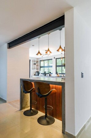 Una cocina moderna con barra, luces colgantes y vistas al exterior.