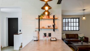 A modern kitchen with a central island, white brick walls, and a dining area with a brown leather sofa.
