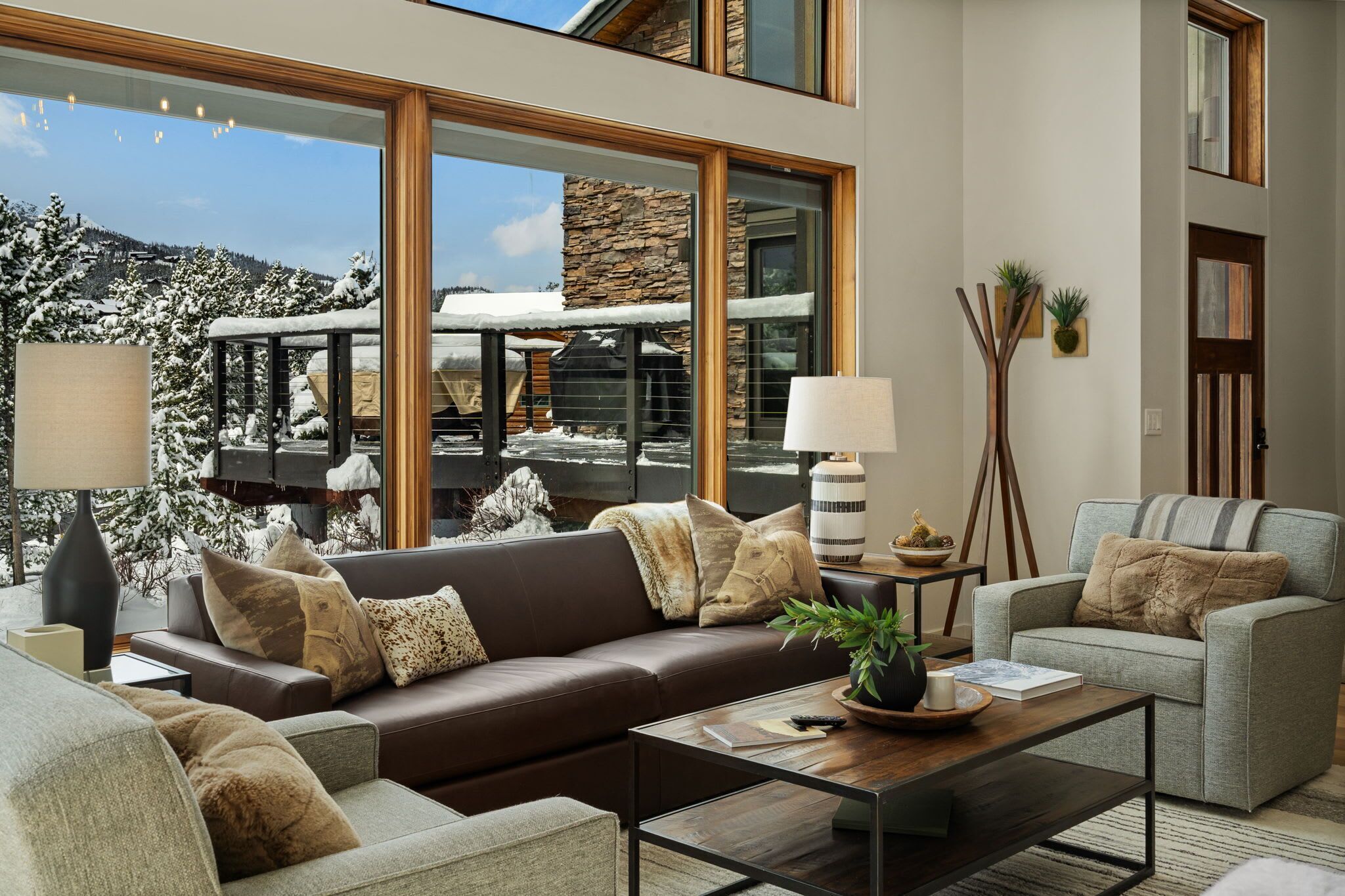 A modern living room with a brown leather sofa, a grey armchair, and a wooden coffee table.
