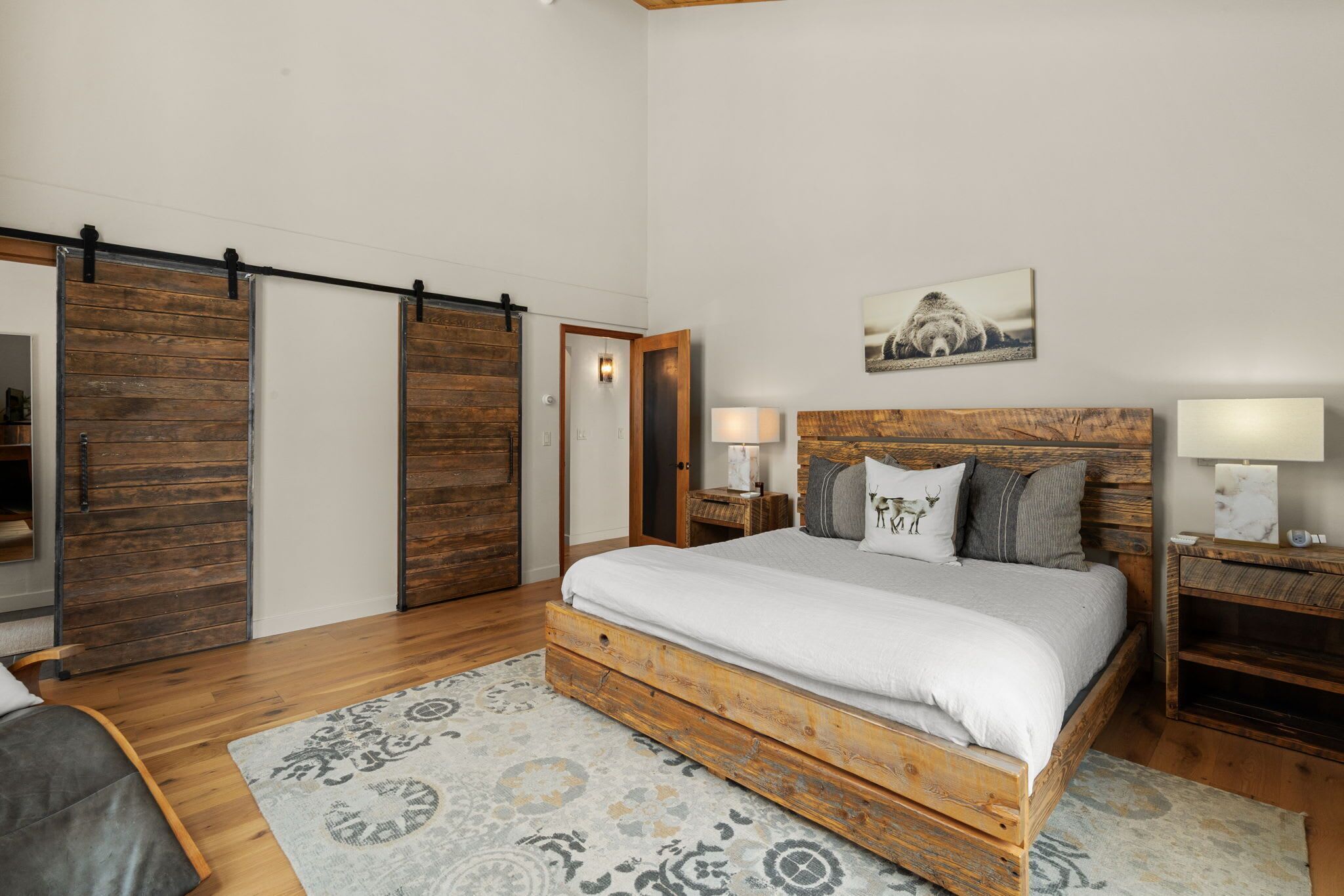 A bedroom with a wooden bed, a nightstand, a lamp, and a sliding door.