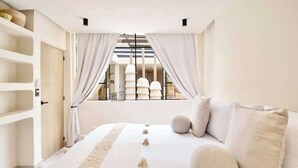 Ein Schlafzimmer mit einem großen Bett, Blick durch ein Fenster und einer Treppe.