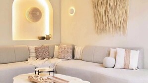 Ein modernes Wohnzimmer mit einer gebogenen Couch, einem runden Couchtisch aus Stein, einem Deckenventilator und einer wandmontierten Leuchte.