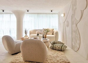 Ein modernes Wohnzimmer mit einer Couch, Sesseln, einem Couchtisch und einer Wanddekoration.