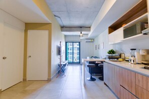 Una cocina moderna con microondas integrado, cafetera y un pequeño comedor con mesa y sillas.
