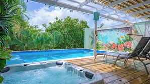 Un jacuzzi, una piscina y un mural con flores tropicales.