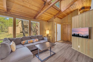 A wooden interior with a sofa, a table, and a TV mounted on the wall. - AC, PF, family friendly, great location, One level (Sunriver)