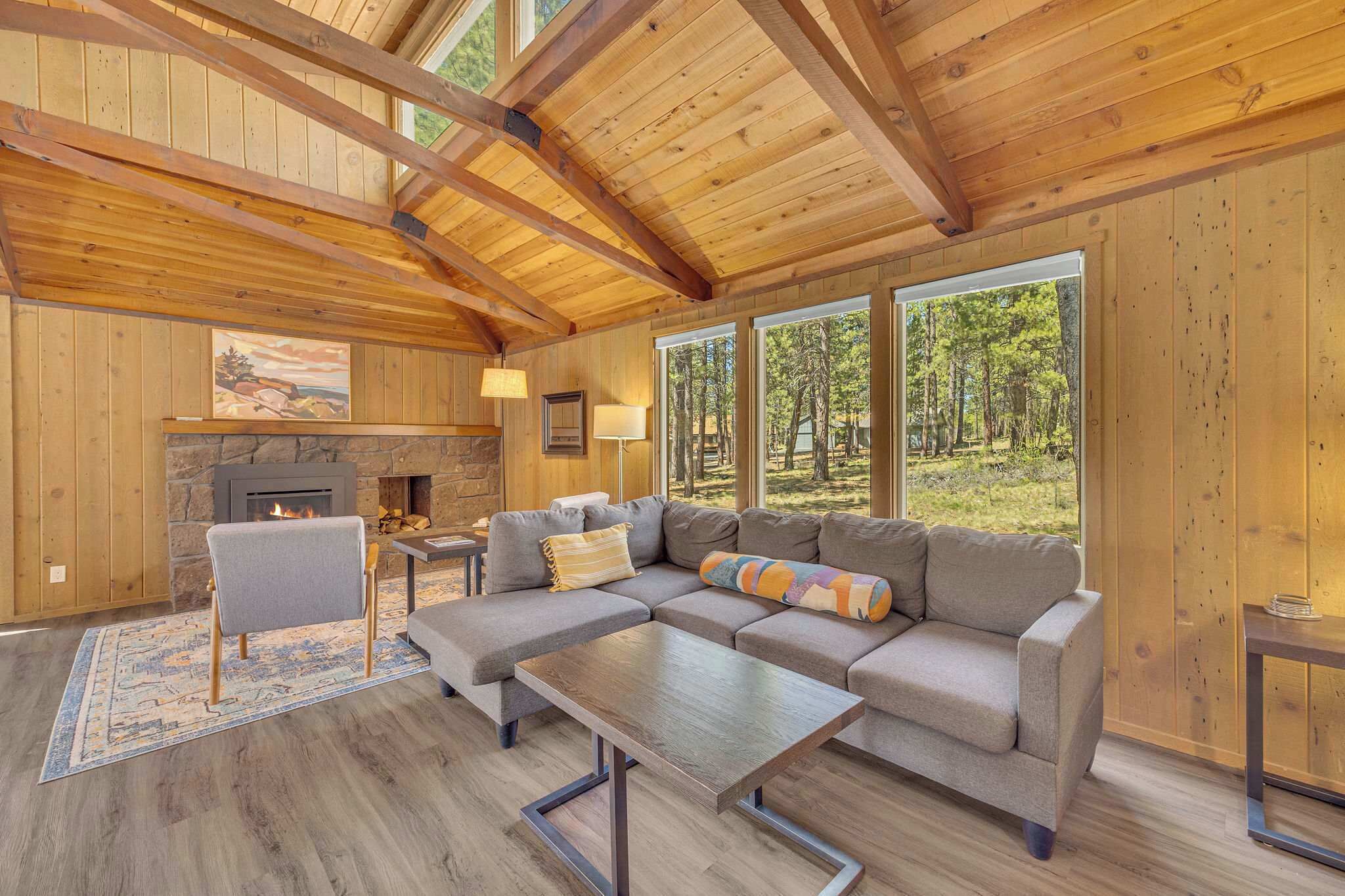 Una sala de estar acogedora con chimenea, ventanas amplias y techo de madera.