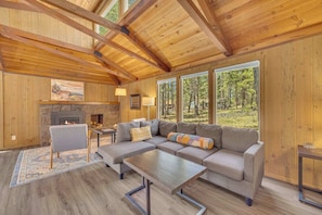 A cozy living room with a fireplace, large windows, and a wooden ceiling. - AC, PF, family friendly, great location, One level (Sunriver)