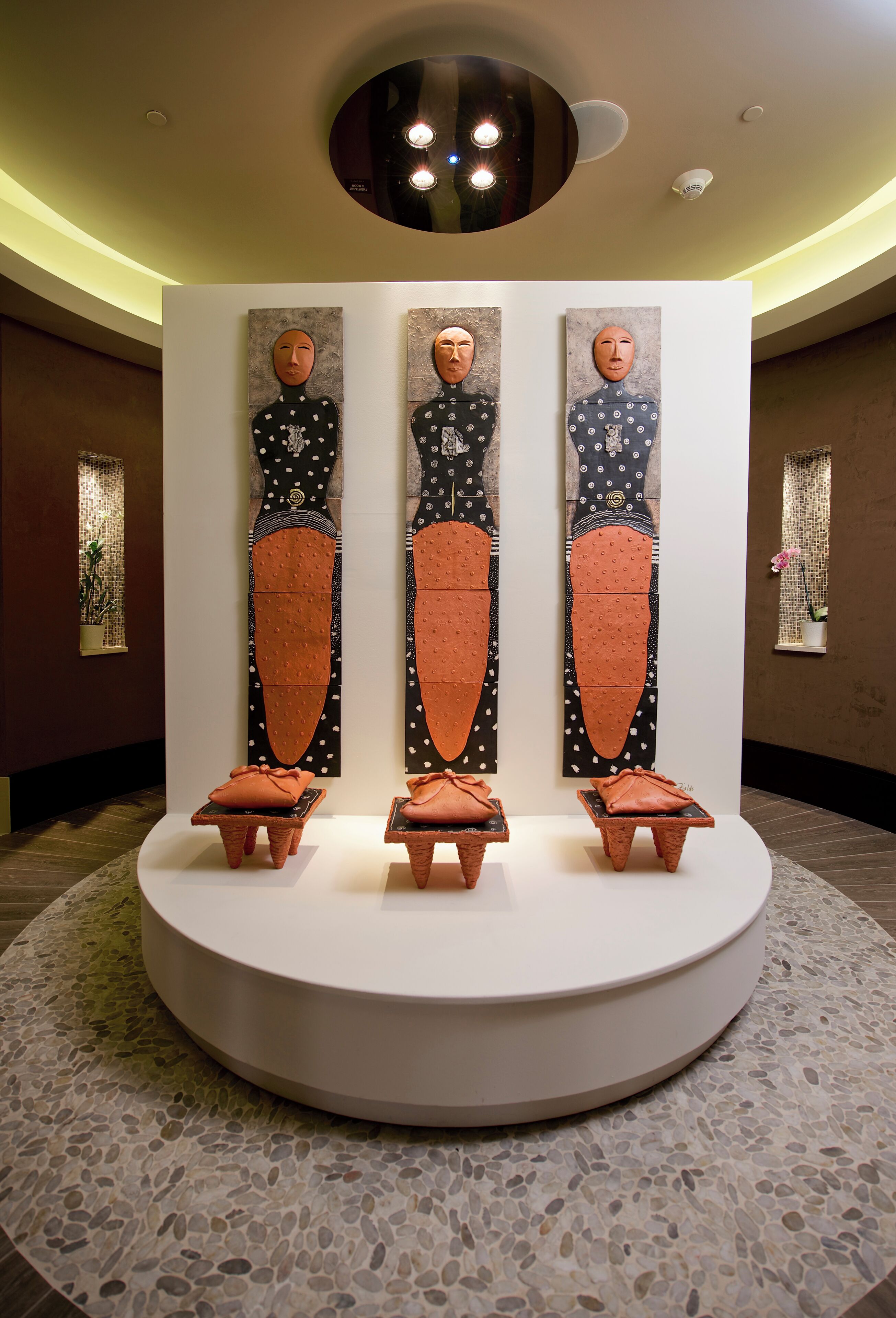 A modern interior with a central display of abstract art, a circular seating area, and a polished stone floor.