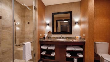 Un baño con cabina de ducha de vidrio, tocador con espejo y retrete.