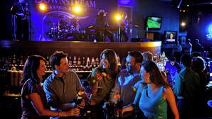 A bar area with a stage for live music, a bar counter, and a visible television screen.