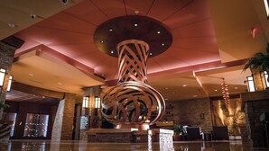 A lobby with a central decorative structure, stone walls, and a polished floor.