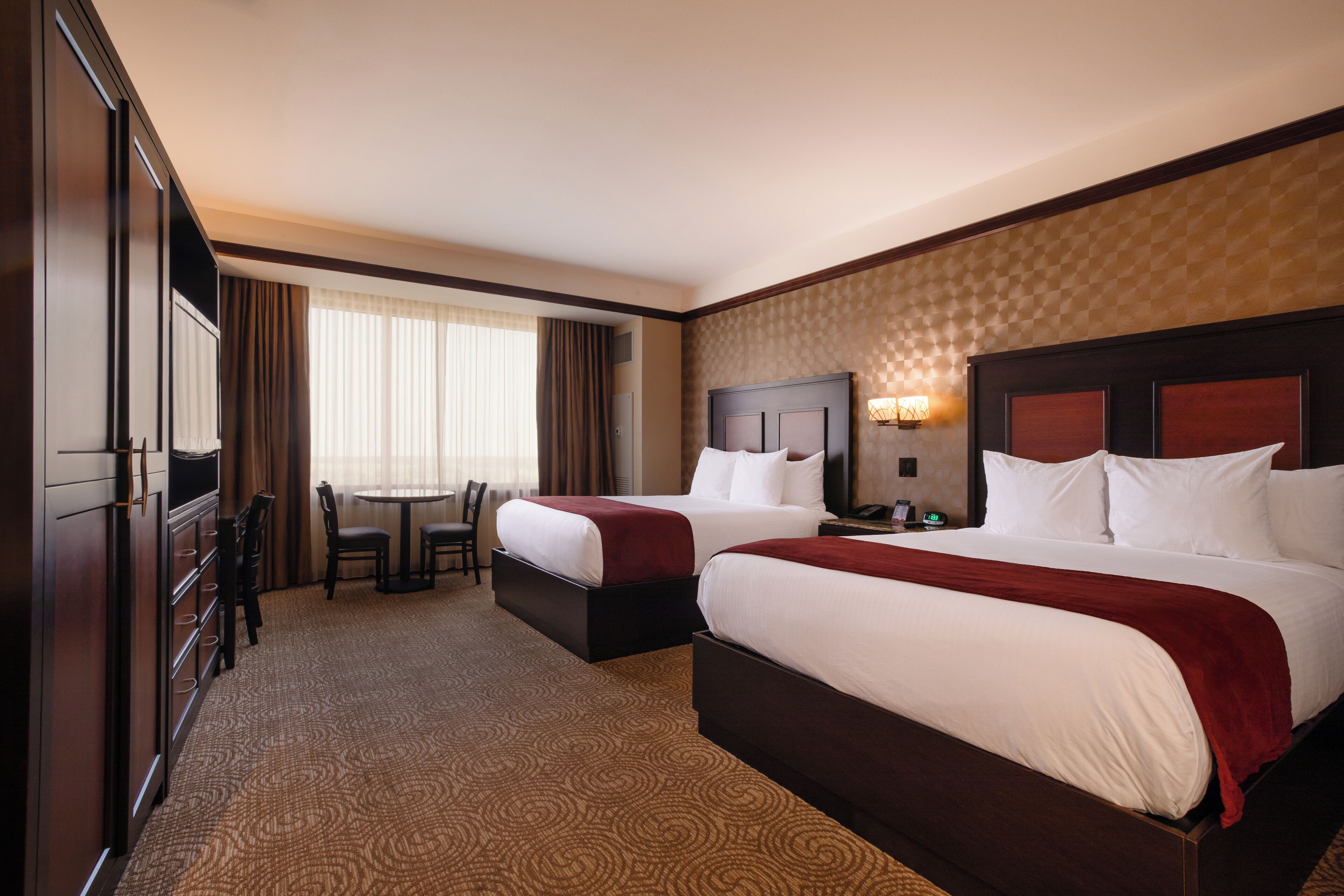 A hotel room with two beds, a desk, and a chair.