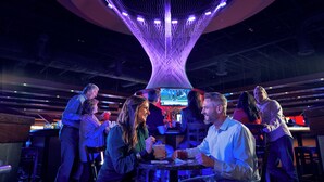 A bar area with a distinctive ceiling structure, tables, and chairs arranged for patrons.