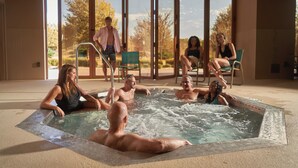 Un área de hidromasaje con cerramiento de vidrio, una piscina y vistas al exterior.