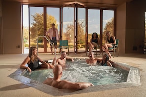 Un área de hidromasaje con cerramiento de vidrio, una piscina y vistas al exterior.
