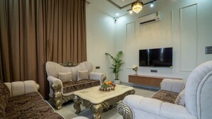 A living room with a sofa, armchairs, a coffee table, a TV, and a potted plant. - Enjoy your staycation in lonavala with our luxurious villa. (Lonavala)